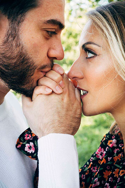 Fotografia di coppia di fidanzati che si guardano negli occhi e si baciano le mani
