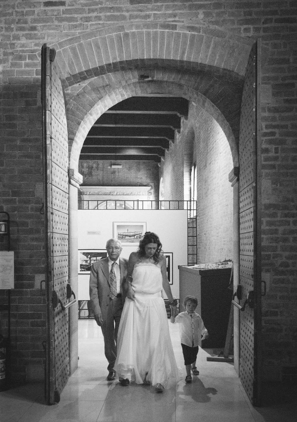 la sposa cammina per i corridoi del comune di cremona accompagnata dal papà e dal figlio