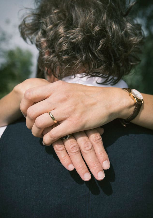 dettaglio delle mani della sposa abbracciata allo sposo