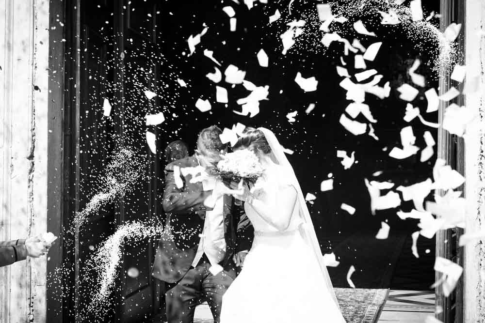foto in bianco e nero degli sposi sotto la pioggia di riso