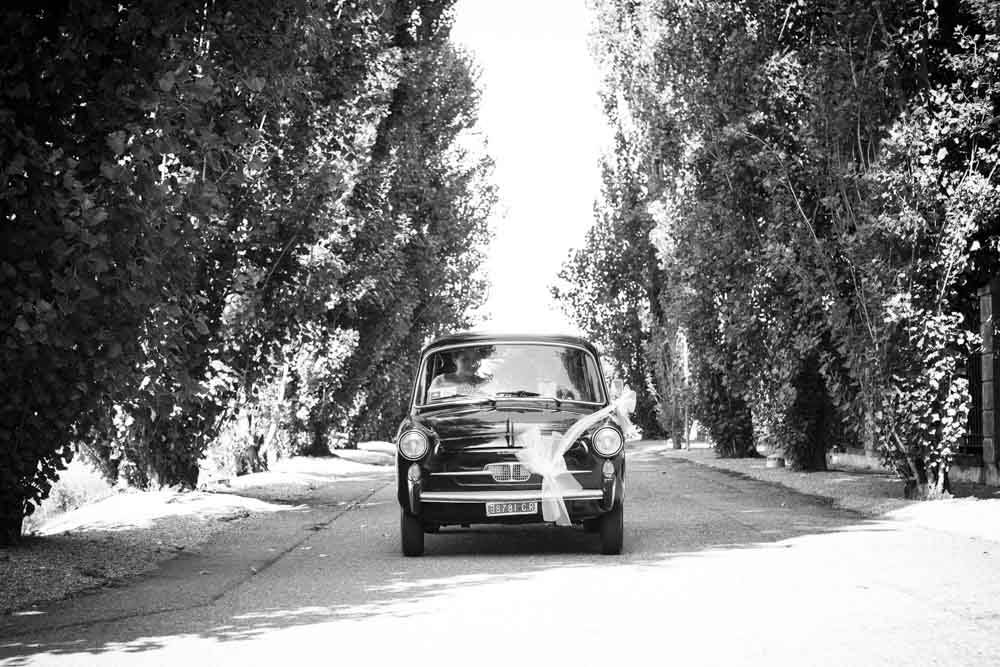 foto in bianco e nero degli sposi a bordo della loro auto nuziale, una Fiat 600 d'epoca