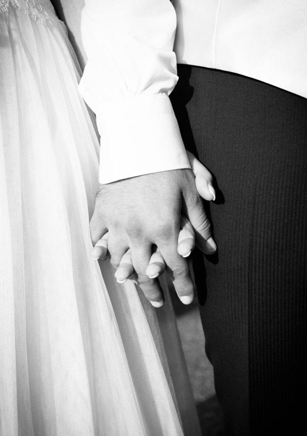 dettaglio in bianco e nero delle mani intrecciate degli sposi